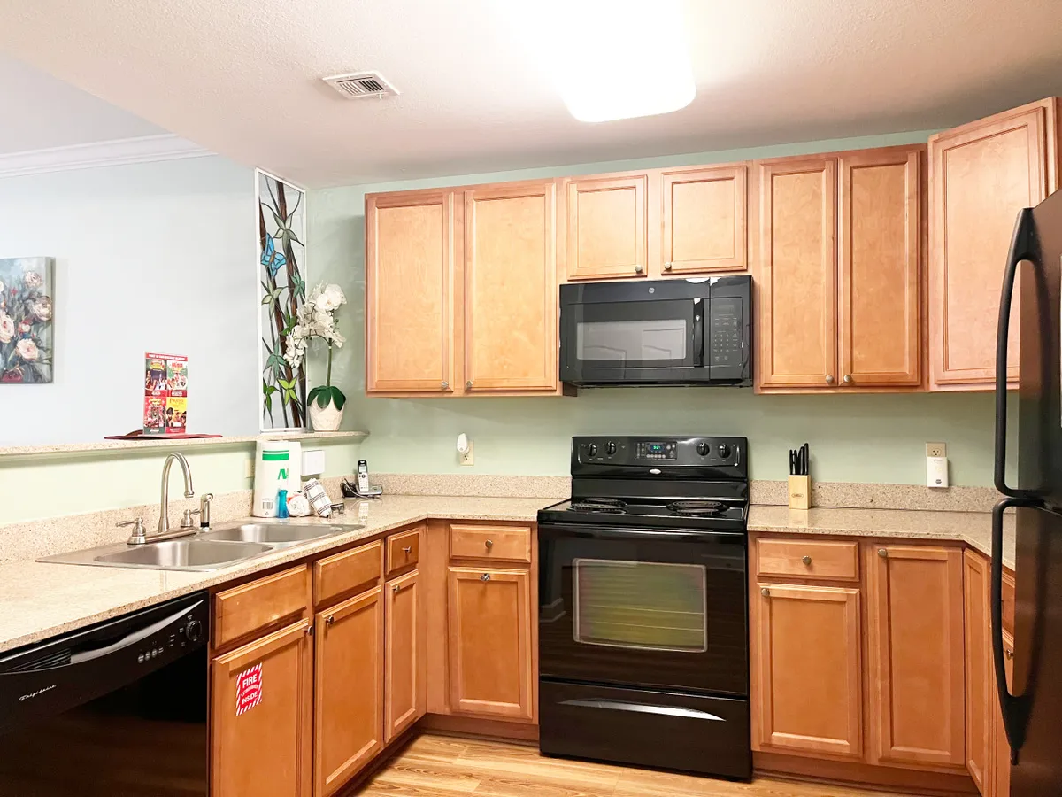 This interior image showcases a well-appointed kitchen with prominent black appliances, generous cabinetry, a sink, and the distinctive touch of a stained glass window. The space is arranged to invite cooking, family gatherings, and entertaining, with visible elements that suggest a fully equipped setup for meal preparation.