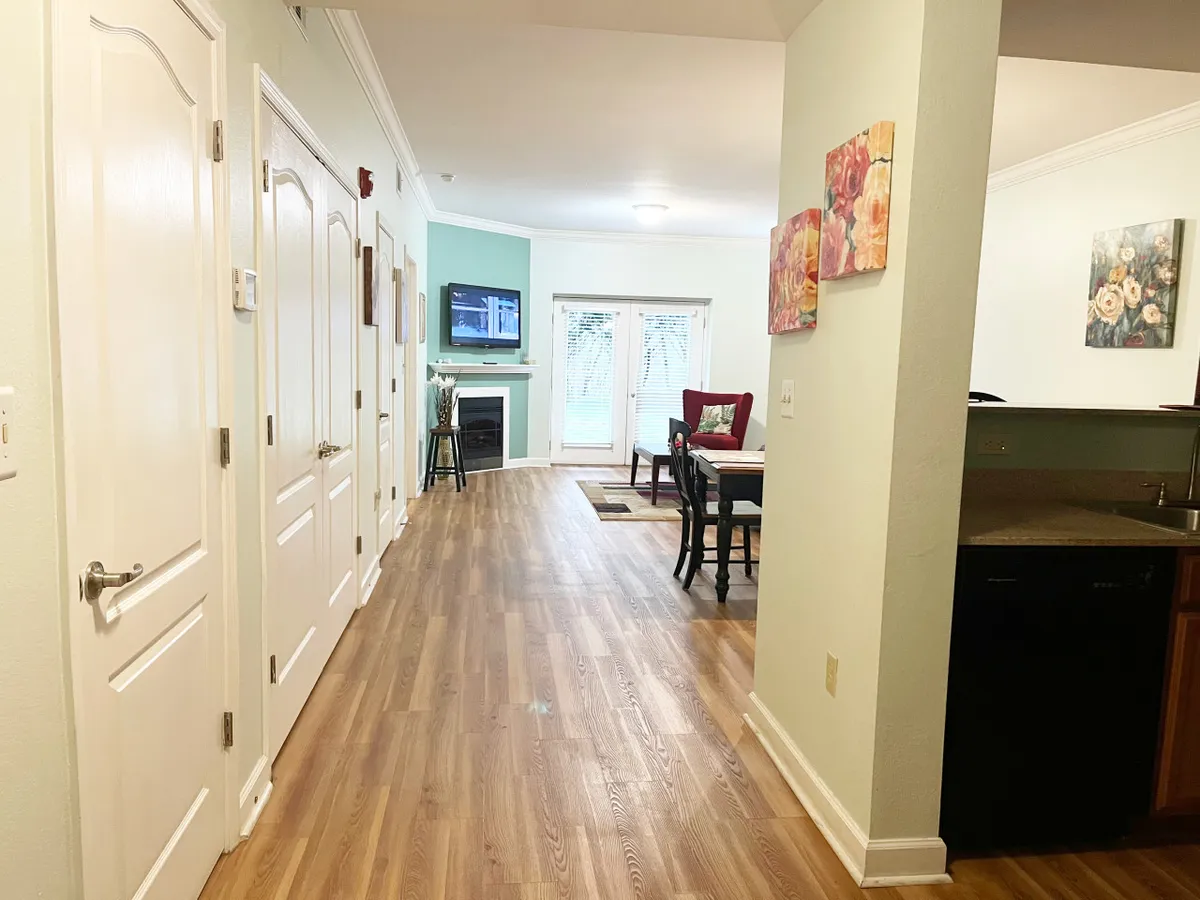 The image presents a cozy and inviting living and dining space, featuring a fireplace, television, dining table, and comfortable seating. The arrangement and decor make it ideal for relaxation and gathering, while large windows suggest ample natural light throughout the area.
