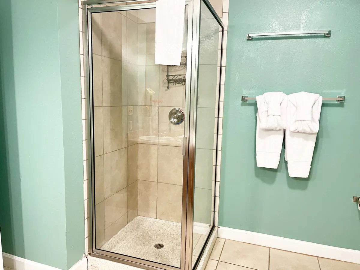This image features a modern bathroom with a glass-enclosed shower, crisp white towels, and elegant tiled flooring. The clean design creates a refreshing and inviting space.
